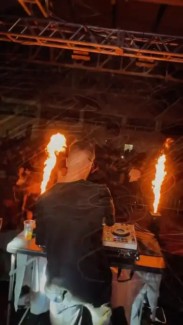 Bruno de costas na cabine, com dois jatos de fogo subindo ao lado do palco