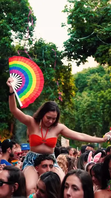 Foliã com leque de arco-íris nos ombros de alguém, no meio do bloco
